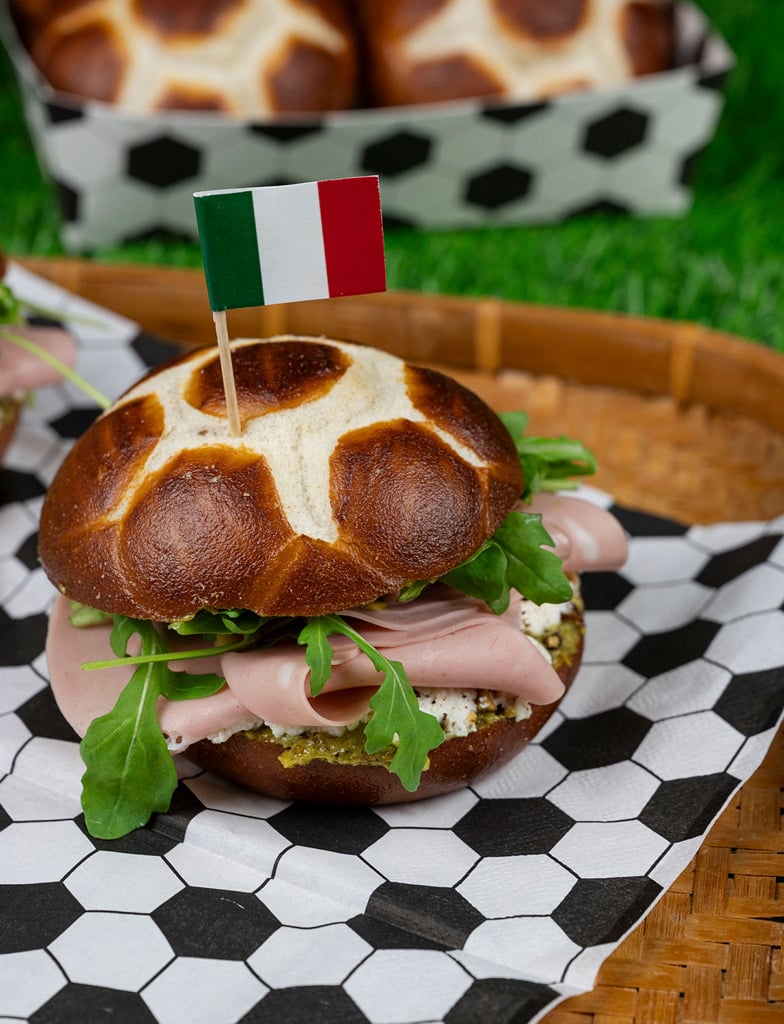 Mortadella and ricotta sandwich with pistachio pesto and arugula on a pretzel soccer bun